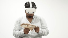 Man wearing virtual reality headset counting a fan of Euro banknotes isolated on a white background - Powered by Shutterstock - Get 15% off with code: PIKWIZARD15