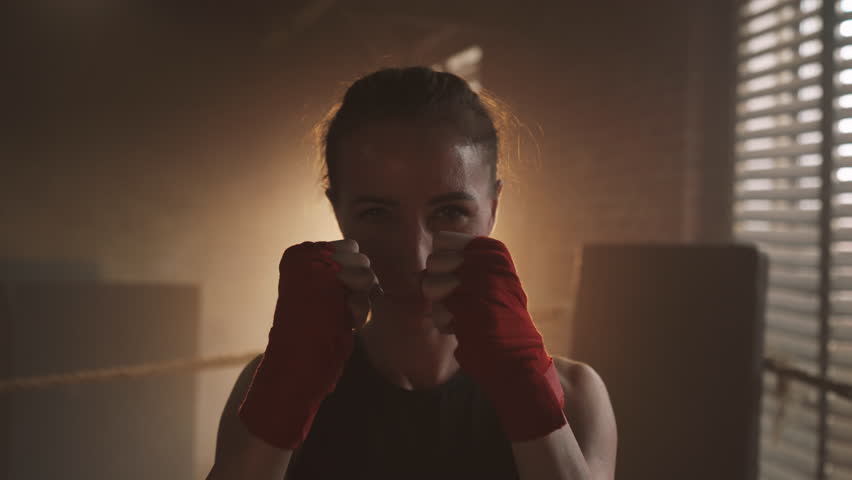 Portrait of athletic woman in pose for punching in boxing club, self-defense. Sports for stay healthy and beautiful, femininity and masculinity, motivated confident sportswoman in static position