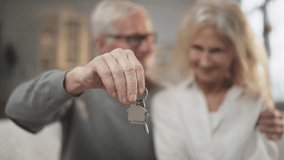 Buy new apartment, keys in hands of elderly man, blurred portrait of aged couple . Mature spouses rejoicing by finish of mortgage, happy house owners, real estate agency, rent, purchase or sale flat - Powered by Shutterstock - Get 15% off with code: PIKWIZARD15