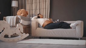 Pregnant woman relaxing in room and listening to classical music by headphones. African american lady enjoying relaxation and calmness, future mother lying on soft couch in bedroom, happy pregnancy - Powered by Shutterstock - Get 15% off with code: PIKWIZARD15