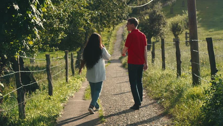 Two friends or a couple enjoy a relaxed walk on a scenic rural countryside and have a happy conversation. Lifestyle slow motion footage