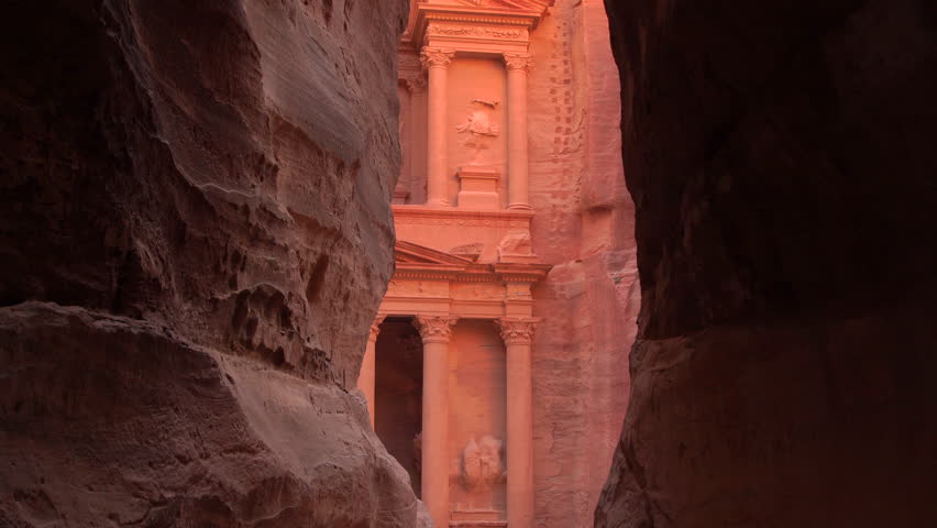 Red sandstone Treasury building (Al Khazneh) framed by the narrow Siq canyon walls in Petra, Jordan.