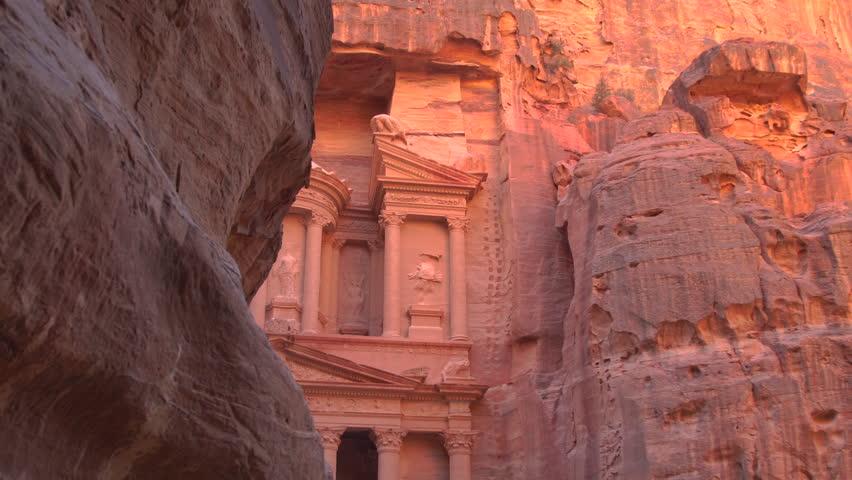The Treasury building, Al Khazneh, seen through the narrow Siq canyon at golden hour in Petra, Jordan.