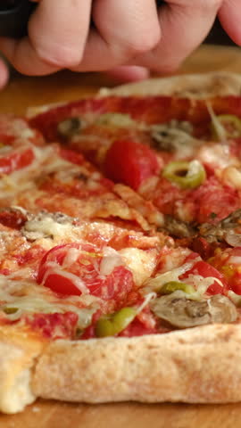 Vertical video. Pizza cutter cuts homemade baked pizza