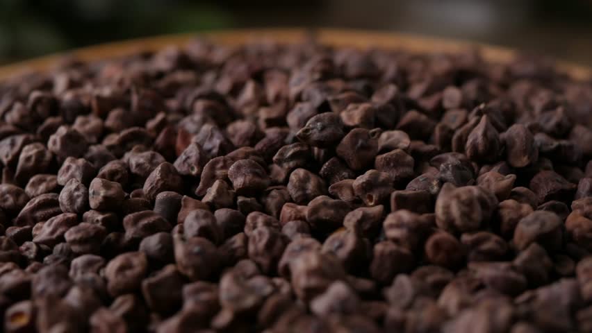 Raw Dark Brown Chickpeas (Kala Chana) on a rustic wooden table. Dry Balck chickpea (ceci neri) background close up.