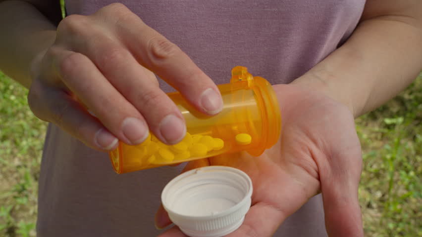 Two painkillers were taken out of the bottle and placed in the woman's hand.

