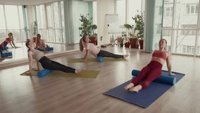 Three women performing foam roller exercises in a fitness studio. - Powered by Shutterstock - Get 15% off with code: PIKWIZARD15