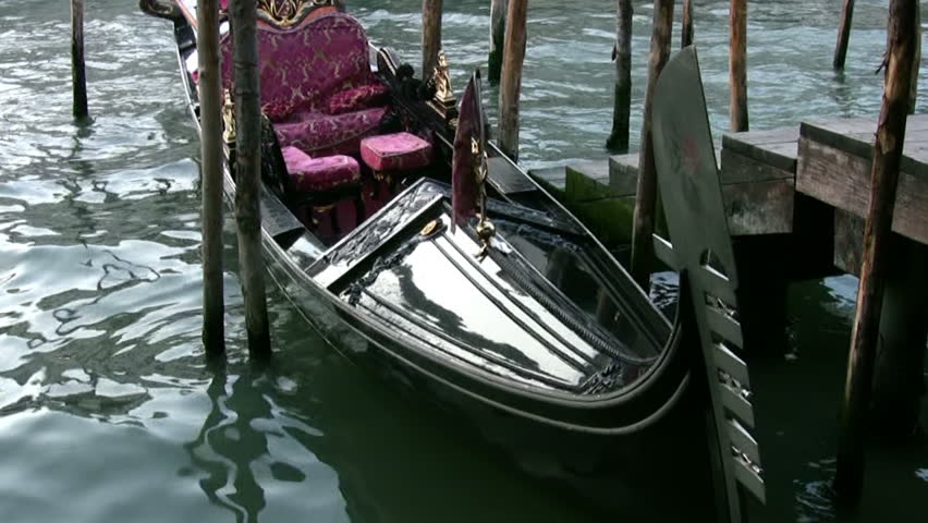 Venice. Grand Canal. Black lacquered gondola sways with the waves. Old wooden