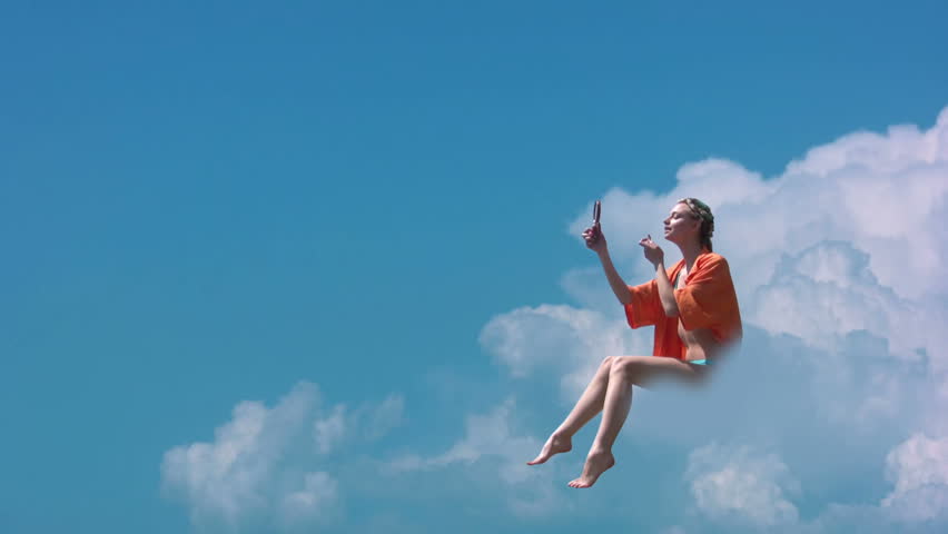 Clear sunny sky. Girl sitting on a cloud and make makeup