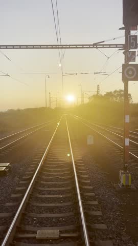 The sun sets beautifully over the railway tracks, painting a picturesque horizon that enhances the tranquility of the rural landscape