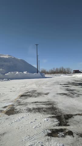 Massive Snow Pile in Icy Parking Lot Under Clear Blue Sky