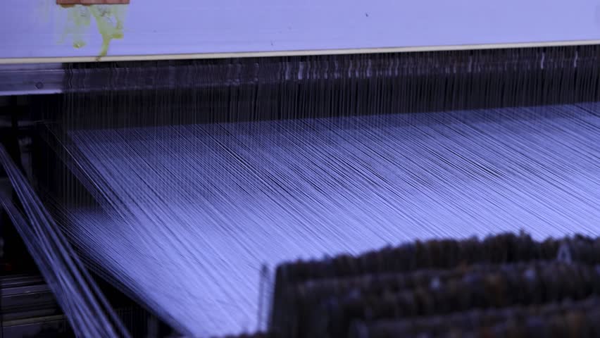 Rotating knitting machine with multiple threads and needles moving rhythmically up and down. Close-up in a textile factory. Precision mechanical motion.
Yarn factory