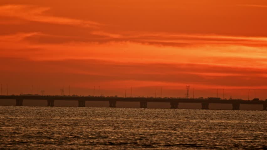 Majestic orange sunset over long bridge and calm sea
