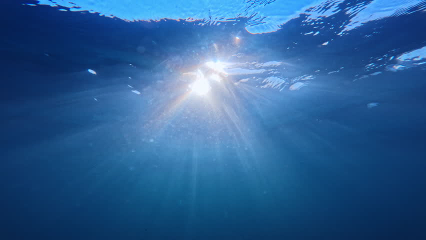 Underwater ocean waves, sun beam and sun rays in blue sea water