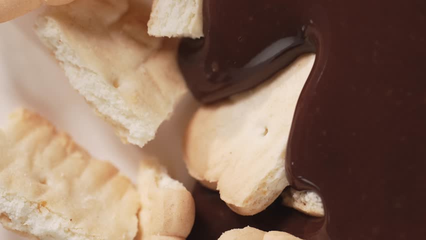 Liquid chocolate pouring on the crushing cookies. 