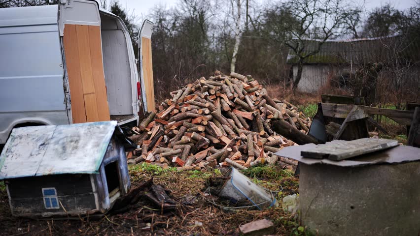 A man unloads firewood from a truck by hand.