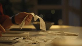Late at night, a person sorts through numerous receipts while calculating expenses. The soft glow of the surrounding light creates a focused atmosphere for financial planning in a cozy home setting - Powered by Shutterstock - Get 15% off with code: PIKWIZARD15