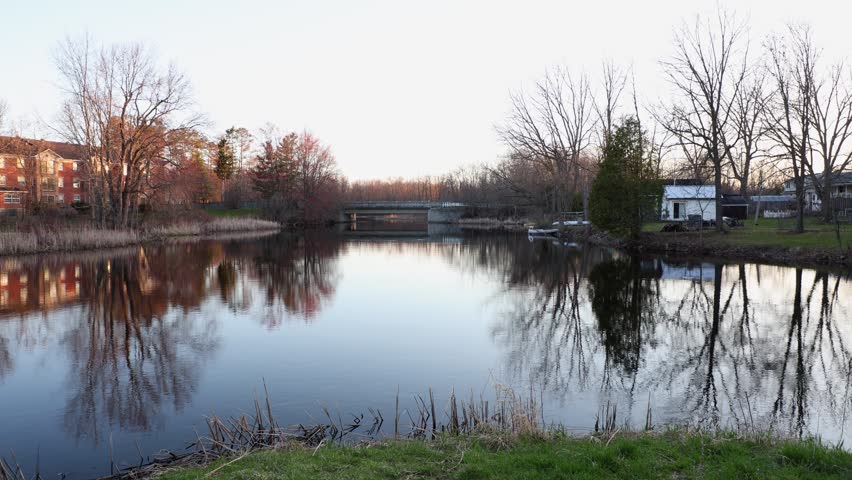 River in Perth, Ontario, Canada. Spring landscape. Reflection of houses and trees in the water.