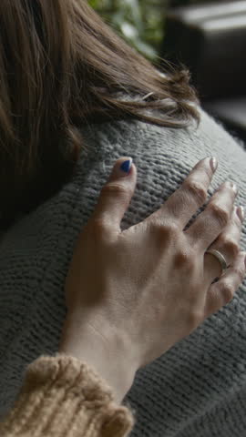 Vertical closeup of crying woman in therapy session, hands clasped in distress, another participant gently placing comforting hand on her shoulder, creating moment of empathy and support