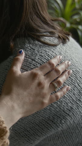 Vertical closeup of crying woman in therapy session, hands clasped in distress, another participant gently placing comforting hand on her shoulder, creating moment of empathy and support