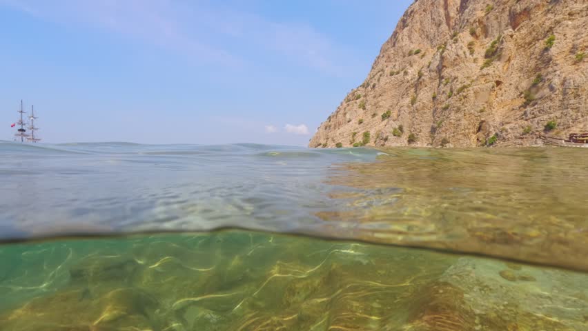 Calm sea water near shore at Butterfly Valley, Oludeniz, boat in distance. Split half underwater video