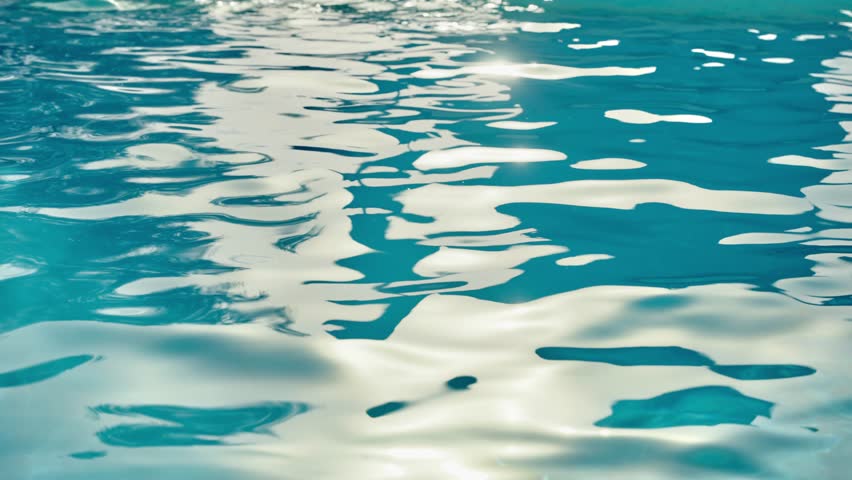 Swimming pool water waves move in pattern in outdoor patio or private pool. Sunny day outside as water move and ripples shine in the sunlight. Wave shapes and abstract turquoise backdrop