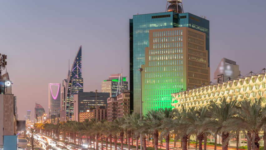Aerial day to night timelapse of King Fahd Road in Riyadh, Saudi Arabia. Bustling traffic with cars and taxis near the illuminated Riyadh National Library, surrounded by modern towers and skyscrapers