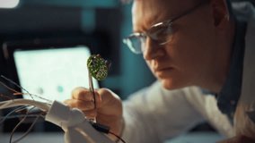 An expert in electronics focuses intensely on a circuit board while using precision tools for repair. This intricate work takes place in a modern laboratory equipped with advanced technology - Powered by Shutterstock - Get 15% off with code: PIKWIZARD15