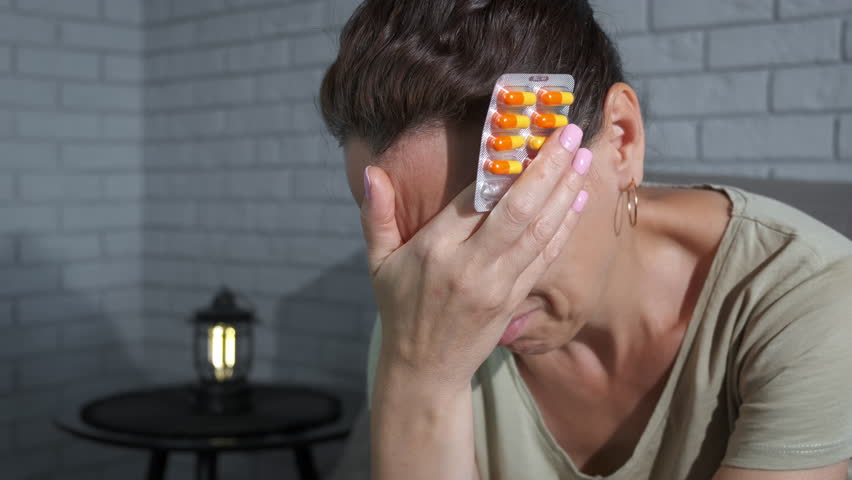 Hold pills against migraine. A woman with pain hold painkillers against migraine in hands. A concept of use medicines for health.