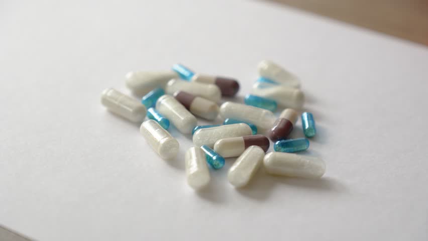Various coloured and white medicine and drug capsules in a group on a table