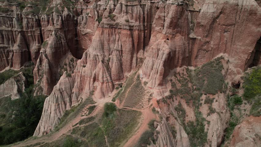 Epic Pullback tilt aerial shot of Rapa Rosie red canyon in Romania. Ascending above beautiful cliffs.