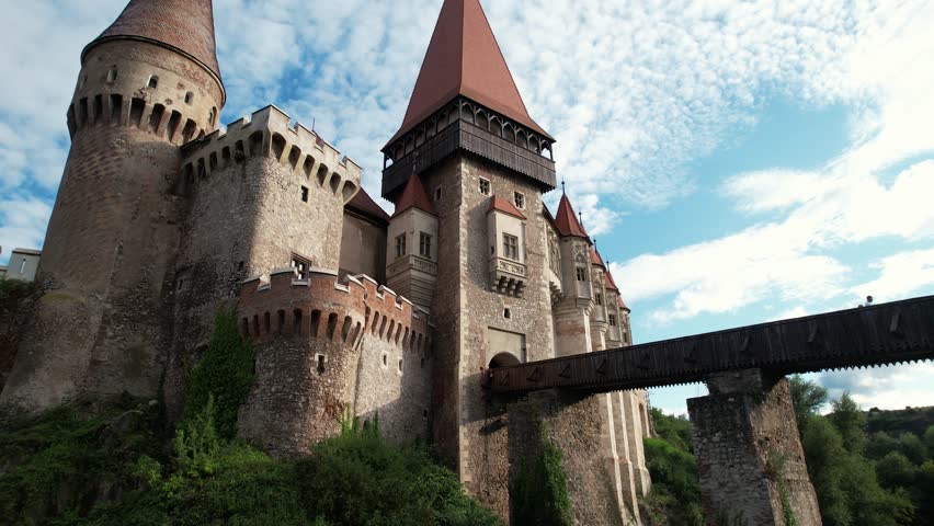 Dramatic drone rise beneath Corvin Castle in Romania. Gothic fortress from below. Epic cinematic shot of medieval landmark in 4K.