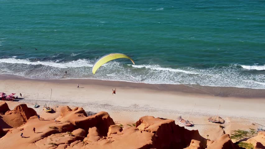 Parasailing Flying In Canoa Quebrada Ceara Brazil. Tourists Parasailing Over A Tropical Ocean On A Sunny Day. Paradise Skyline Idyllic Wanderlust. Paradise Sea. Canoa Quebrada Ceara.