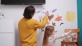 Father and daughter painting on a white wall in a playful and creative moment - Powered by Shutterstock - Get 15% off with code: PIKWIZARD15