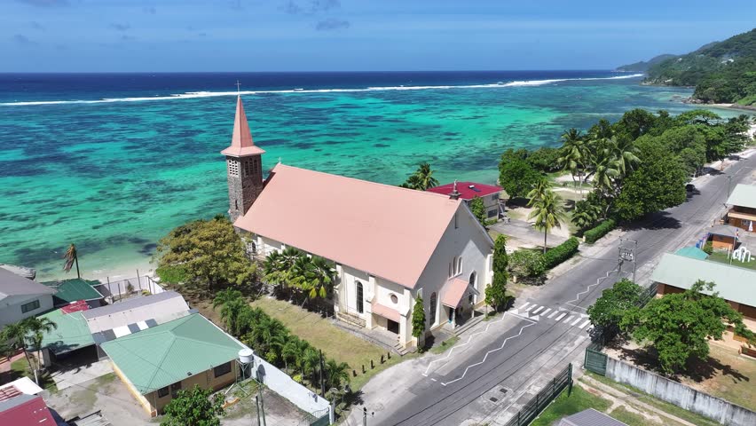 Church Beach In Anse Royale Beach Mahe Island Seychelles. Aerial View Of Church Building Dominating The Skyline. Shore Horizon Beach Sea. Seaside Panning Wide. Anse Royale Beach Mahe Island.
