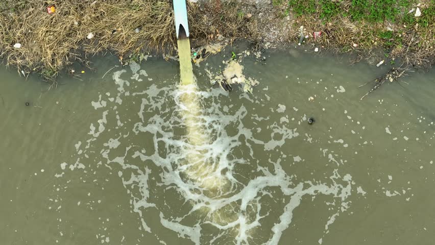 Water flows from a pipe into an agricultural waterway, demonstrating irrigation practices essential for crop growth and efficient water management in farming.
