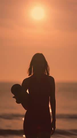 A peaceful silhouette of a woman holding a yoga mat while standing by the beach at sunset. Ideal for wellness, fitness, or meditation themes, this image conveys serenity, relaxation, and outdoor