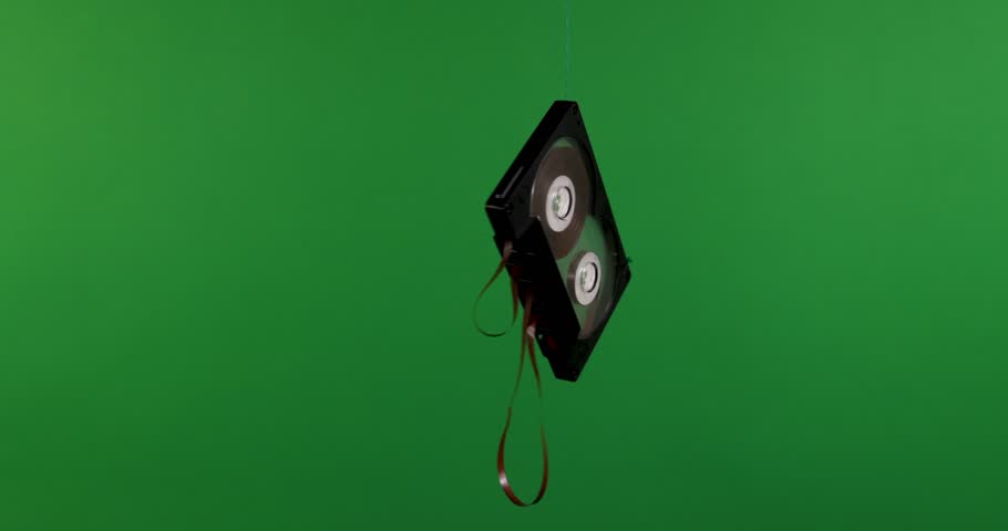 A VHS tape floating elegantly in the air, surrounded by numerous hands, set against a vibrant green background