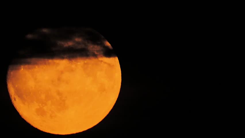 huge orange moon rises up in the evening sky
