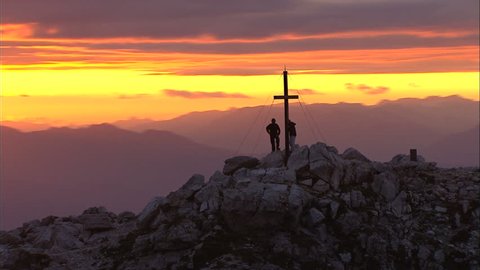 Sunset over the Mountains / Italy / Alp. People stand near cross silhouetted on mountain with flare.  Stock Video