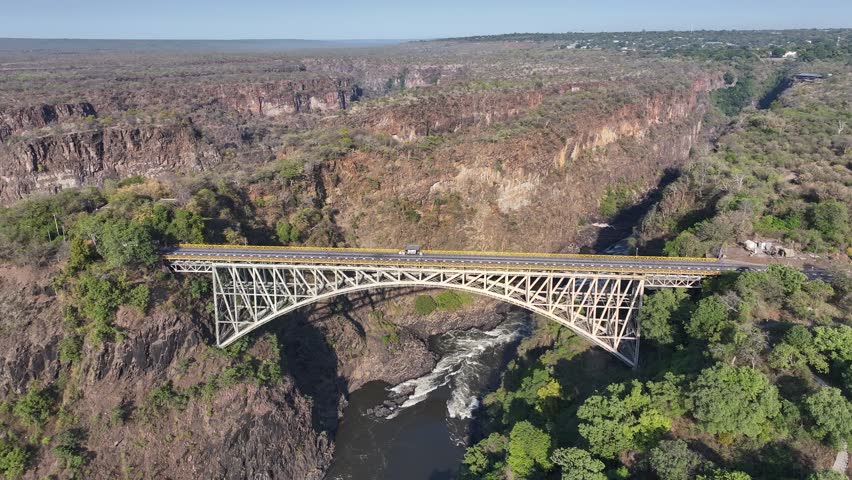 Bridge Border In Victoria Falls Matabeleland North Zimbabwe. Birds Eye View Of Suspension Bridge With Cars Driving Across. Landscape Sky Waterfall Tropical. Outside Waterfall Panorama.