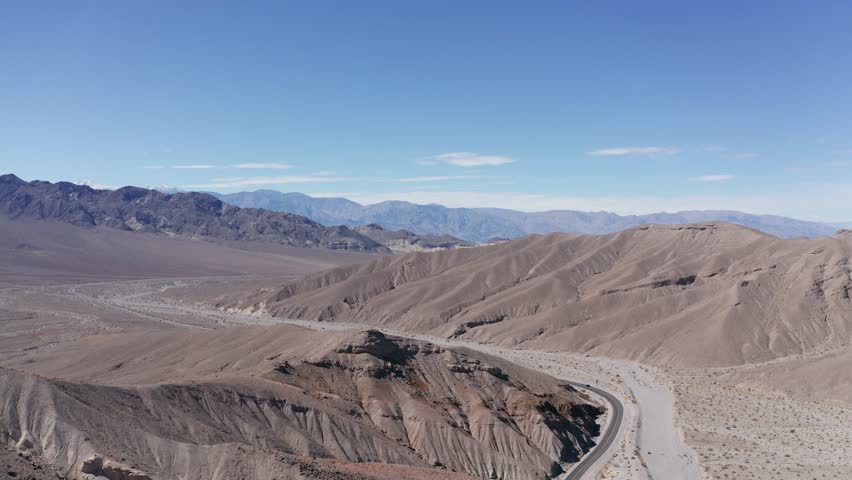 Wide panning aerial shot of a desert road leading into Death Valley National Park, California. 4K