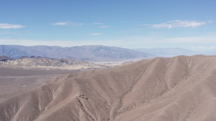 Aerial high panning shot revealing Furnace Creek in the distance outside Death Valley National Park, California. 4K