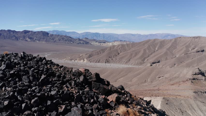 Aerial close-up dolly shot of a rocky desert ridge above the entrance to Death Valley National Park, California. 4K