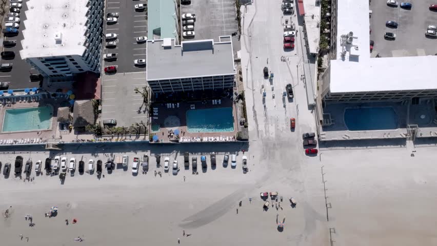 Daytona Beach, Florida with vehicles, and people on the beach with drone video overhead looking down.
