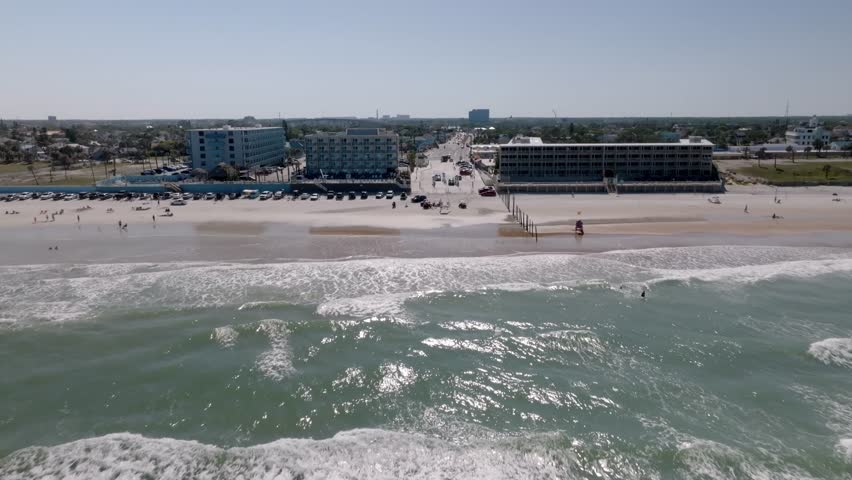 Daytona Beach, Florida with vehicles and people on the beach with drone video moving in.