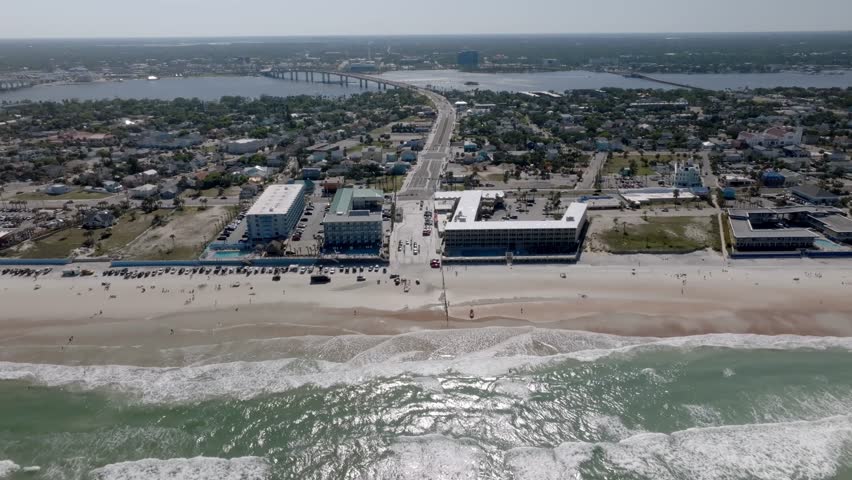 Daytona Beach, Florida with vehicles and people on the beach with drone video moving right to left.