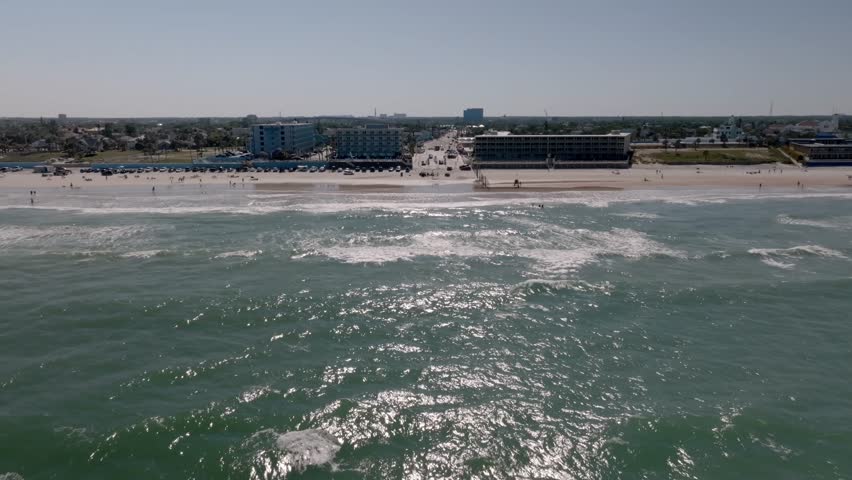 Daytona Beach, Florida with vehicles and people on the beach with drone video moving in wide shot.