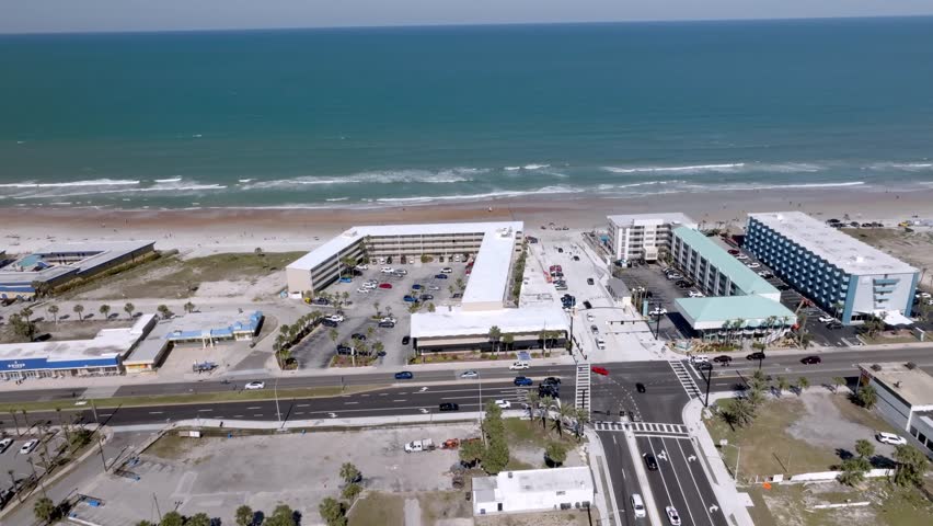 Daytona Beach, Florida with waves from the Atlantic Ocean, vehicles, hotels and people on the beach with drone video stable.