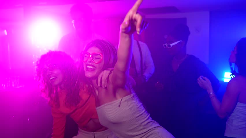 Women dancing and enjoying vibrant music with friends, sharing infectious energy at bustling nightclub party with pulsing beats and colorful atmosphere